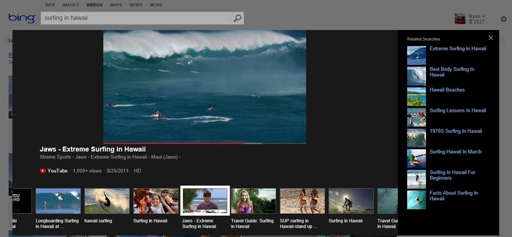 Bing video search results for "surfing in Hawaii," featuring a highlighted YouTube video titled "Jaws - Extreme Surfing in Hawaii." The preview shows surfers on large waves. Below are related video thumbnails, and a sidebar lists related searches.