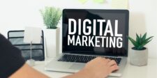 A person using a laptop displaying the words "DIGITAL MARKETING," with plants and office supplies on the desk. | digital marketing experts