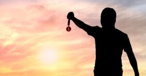 A man raises a key above his head against a vibrant sunset backdrop, symbolizing hope and new beginnings.