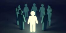 A glowing figure stands surrounded by darker figures, symbolizing leadership or standing out. | famous introverted leaders