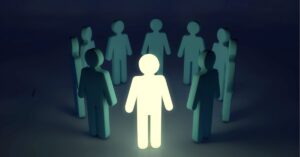 A glowing figure stands surrounded by darker figures, symbolizing leadership or standing out. | famous introverted leaders