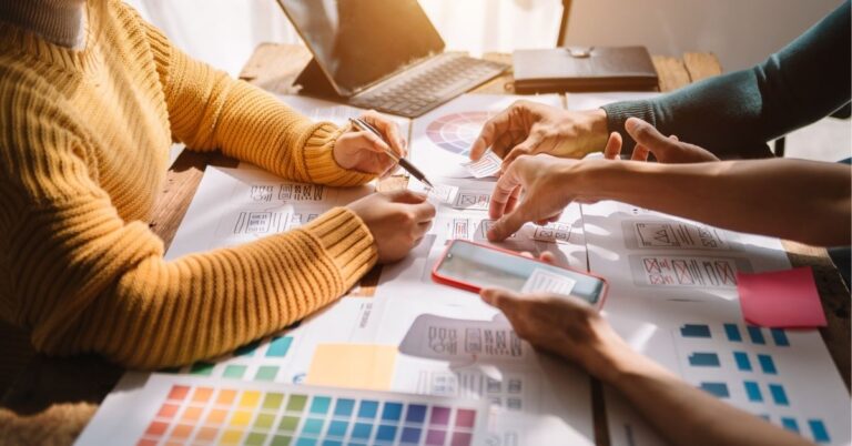 "Team brainstorming over design layouts with color palettes and digital devices."