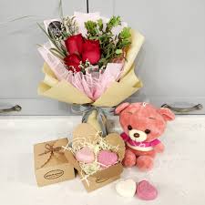 Bouquet of red roses with a pink teddy bear and heart-shaped soaps.