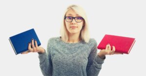 A woman with glasses holding a red book in one hand and a blue book in the other, shrugging as if deciding between them—symbolizing how to deal with someone who has unrealistic expectations by presenting choices.