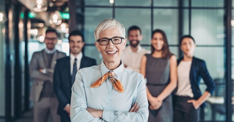 Confident businesswoman standing in front of her team in an office.