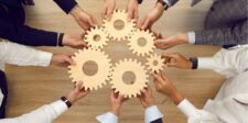 Hands holding interlocking wooden gears, symbolizing teamwork.