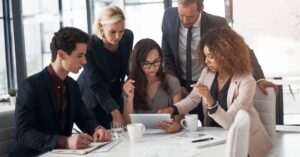 Team collaborating around a tablet in a modern office setting.