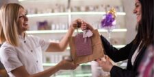 Customer receiving a gift bag from a smiling shop assistant in a boutique.