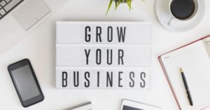 Desk setup with a lightbox reading "Grow Your Business." | work on your business