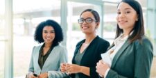 Three confident professionals smiling in an office setting.