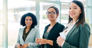 Three confident professionals smiling in an office setting.