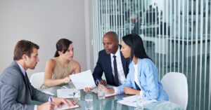 Team engaged in a focused business discussion at a glass table.