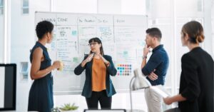 Team discussing project tasks in front of a whiteboard filled with notes and charts.