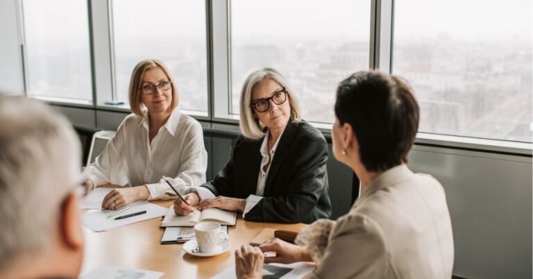 Three women in a business meeting, engaged in discussion around a table.