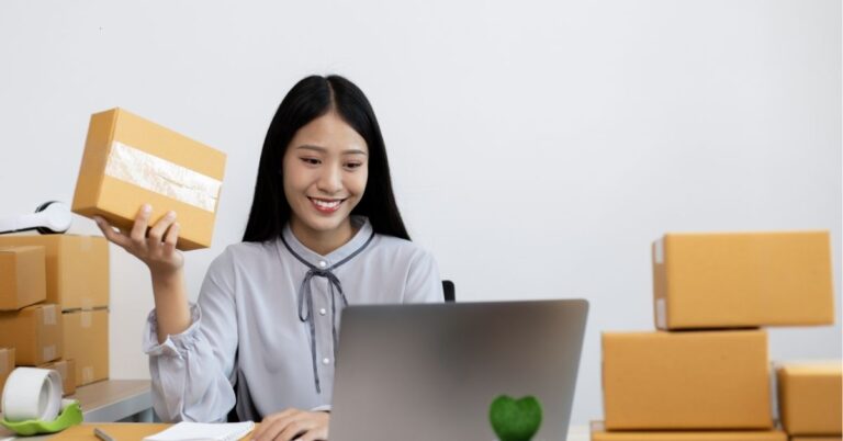 Woman smiling and holding a package while working on a laptop. Text: "Boost Your Online Sales! Effective Tips for E-commerce Success."
