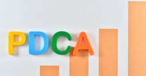 Colorful letters "PDCA" with a bar graph in the background.