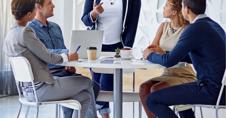 Team of professionals having a meeting around a table with laptops and notes.