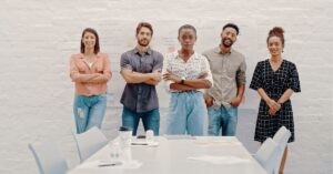 Team of five standing confidently in front of a whiteboard with notes and diagrams.