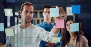 Team brainstorming with sticky notes on glass.