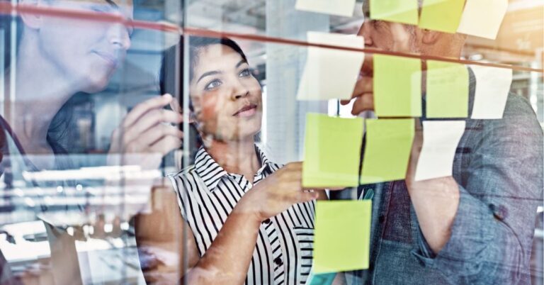 Team brainstorming with sticky notes on a glass wall.