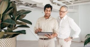Two professionals collaborating on a tablet in a modern office.