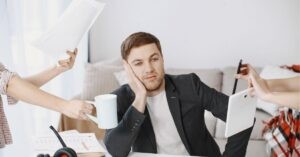 Person overwhelmed with tasks, surrounded by hands offering items like coffee, documents, and a tablet.