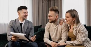 A businessperson in a suit discussing documents with a smiling couple.