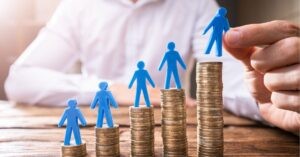 Plastic figures on stacks of coins, symbolizing growth and success.