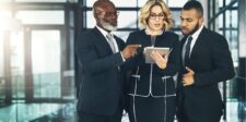 Three business professionals discussing something on a tablet.