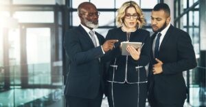 Three business professionals discussing something on a tablet.