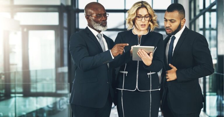 Three business professionals discussing something on a tablet.