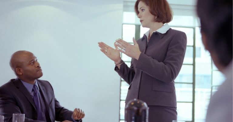 Business meeting with a woman speaking and a man listening attentively.