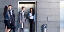 What Is an Elevator Pitch and Why You Need One for Growth Four business professionals in suits conversing near an elevator.