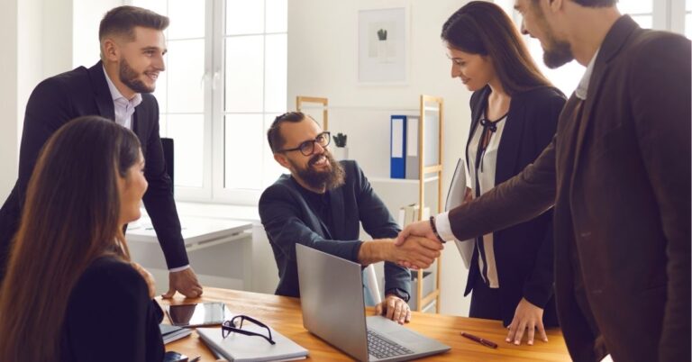 Team meeting with handshake across a table.