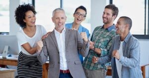 A team of professionals celebrating success in the office, representing the clarity and alignment achieved using the StoryBrand framework.