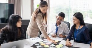 Team collaborating around a table with sticky notes and documents.