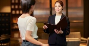 Two professionals having a conversation, one holding a folder and smiling.