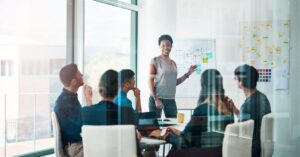 Team meeting with a presenter at a whiteboard in a conference room.