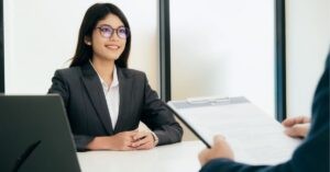 Person in a suit smiling during a meeting or interview.