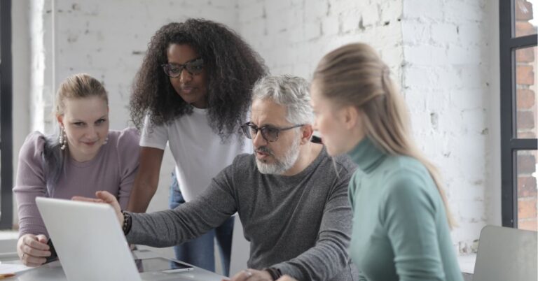 Team collaborating around a laptop in an office setting.