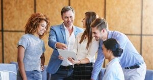 Team of professionals collaborating and smiling while looking at a tablet.