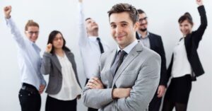 Confident professional in front of a cheering team, showcasing leadership and success.