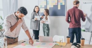 Team collaborating in an office with sticky notes and a whiteboard.