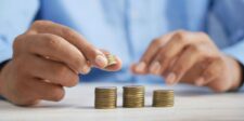 Person organizing coins into three stacks to illustrate the One-Third Rule for smarter money management and budgeting.