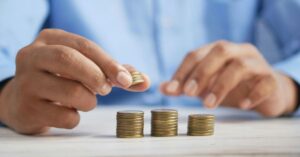Person organizing coins into three stacks to illustrate the One-Third Rule for smarter money management and budgeting.
