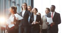 Group of business professionals walking confidently in an office corridor.