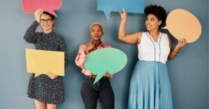 Three women holding colorful speech bubbles.