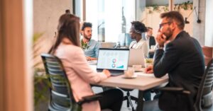 Team in a meeting discussing strategies with laptops and charts.