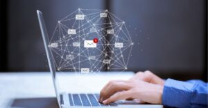 Hands typing on a laptop with email notifications and digital connections above.