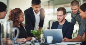 Person using a laptop at a café: Individual typing on a laptop with a coffee cup nearby, focusing on digital marketing tasks.